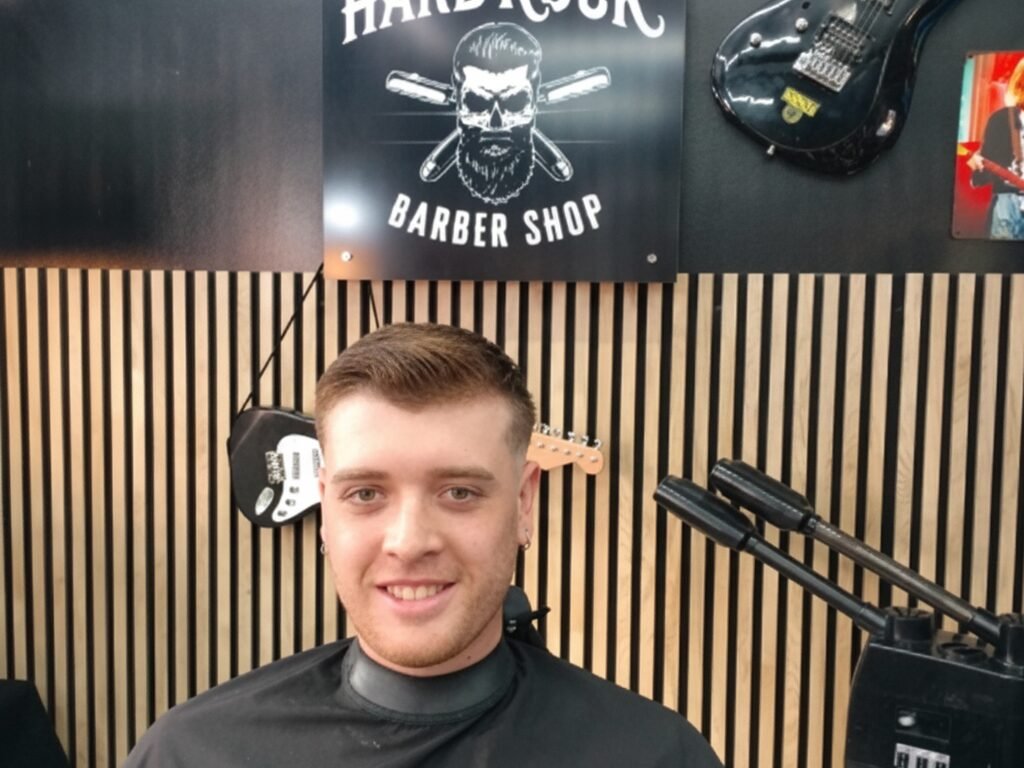 Cliente sonriente tras su corte, con guitarras al fondo